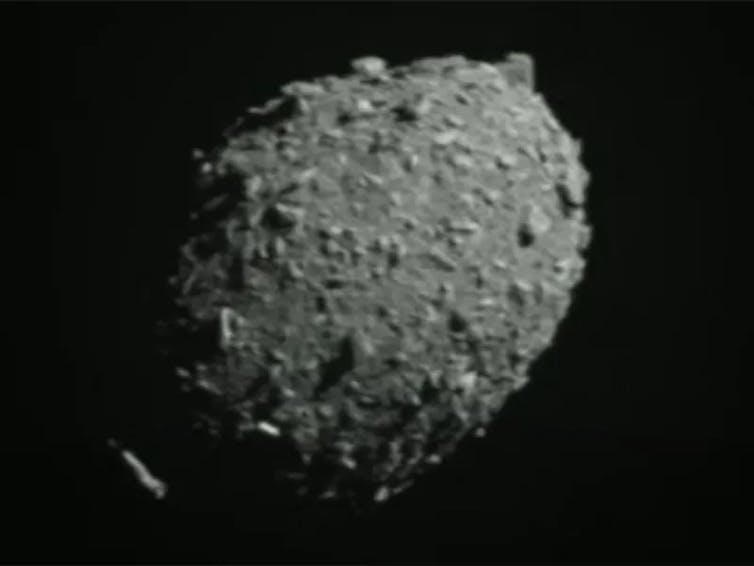 A slightly blurry image of a grey rock that looks a bit like a potato on a black background.